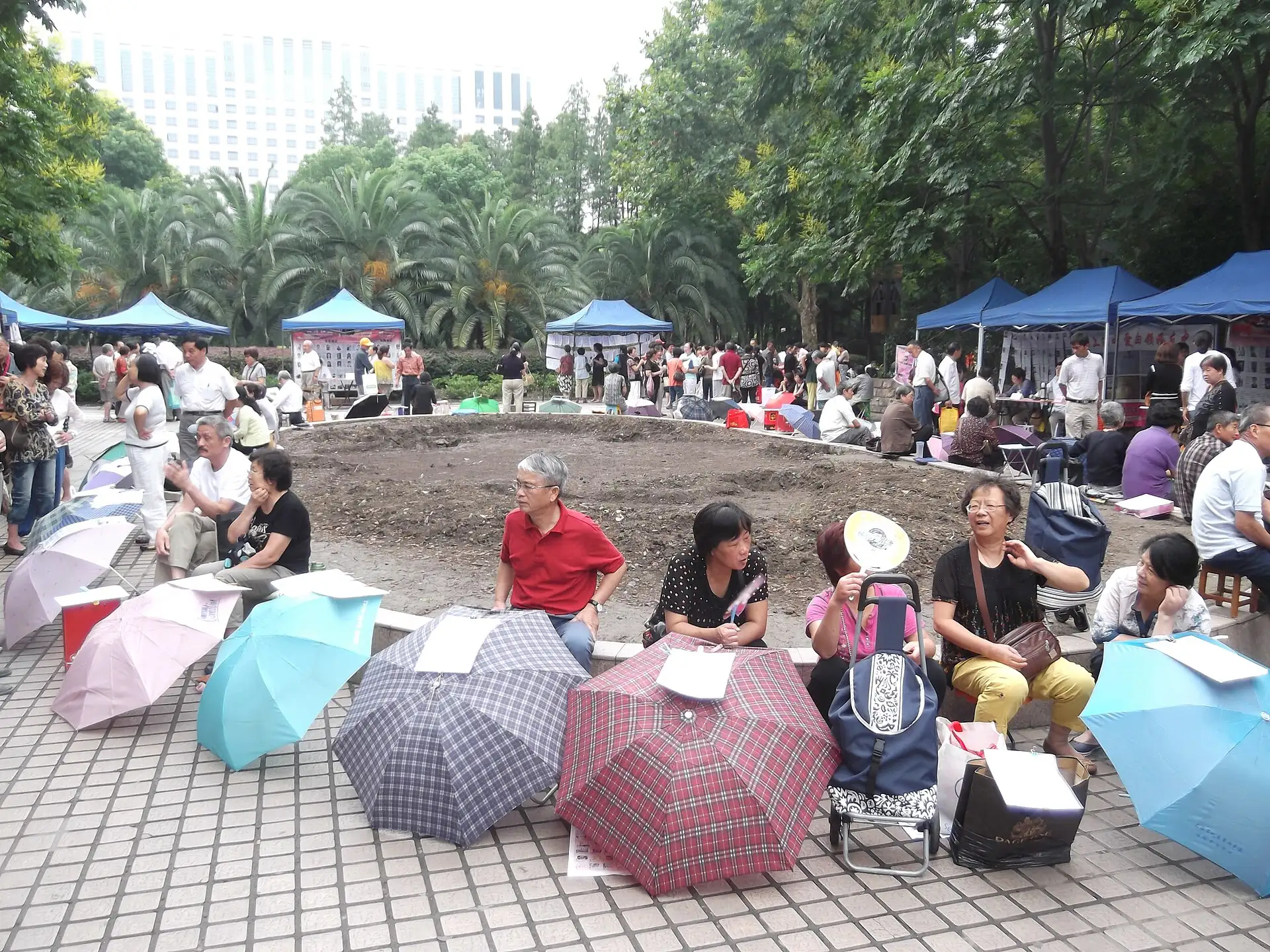 Umbrellas at the marriage market in People's Park, Shanghai, with stalls in the background.