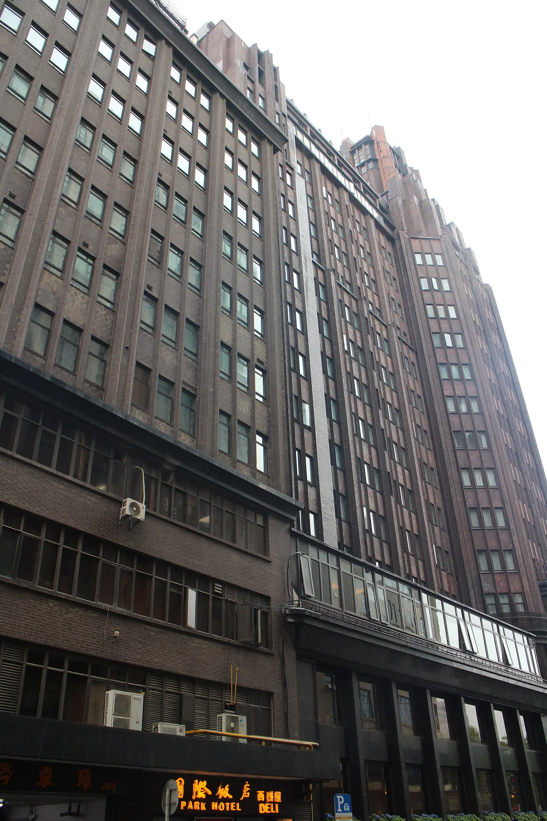 The Park Hotel's dark brick tower seen from the street below, stepping back as it rises.