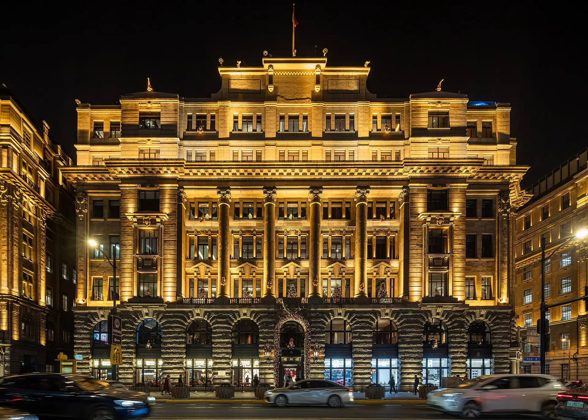 The Jardine Matheson Building lit up at night, a stone façade with giant columns above the ground floor.