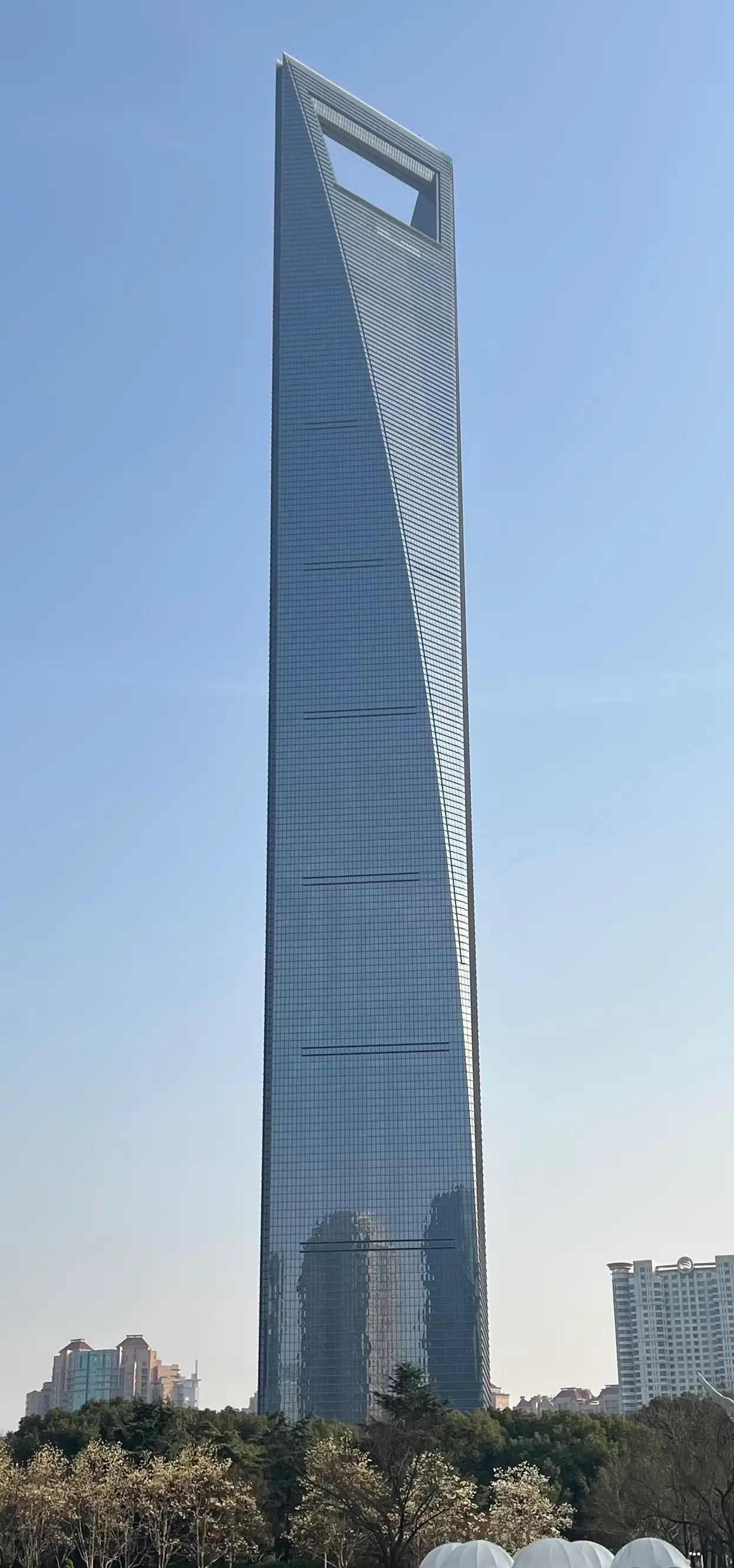 The Shanghai World Financial Center, a tall glass tower with a trapezoid opening at the top.