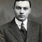 Black-and-white studio portrait of a young clean-shaven man in a tweed jacket and dark tie.
