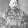 Black-and-white portrait of a man with a moustache wearing a Qing hat and a heavy fur coat.