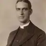 Sepia studio portrait of a clean-shaven man in a dark clerical jacket with a white collar.
