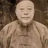 Sepia portrait of an older man in a small cap and a patterned silk jacket, on a cracked and stained print.