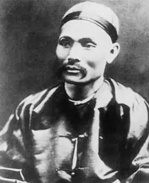 Black-and-white portrait of a man with a moustache wearing a skullcap and a dark silk jacket with toggle buttons.