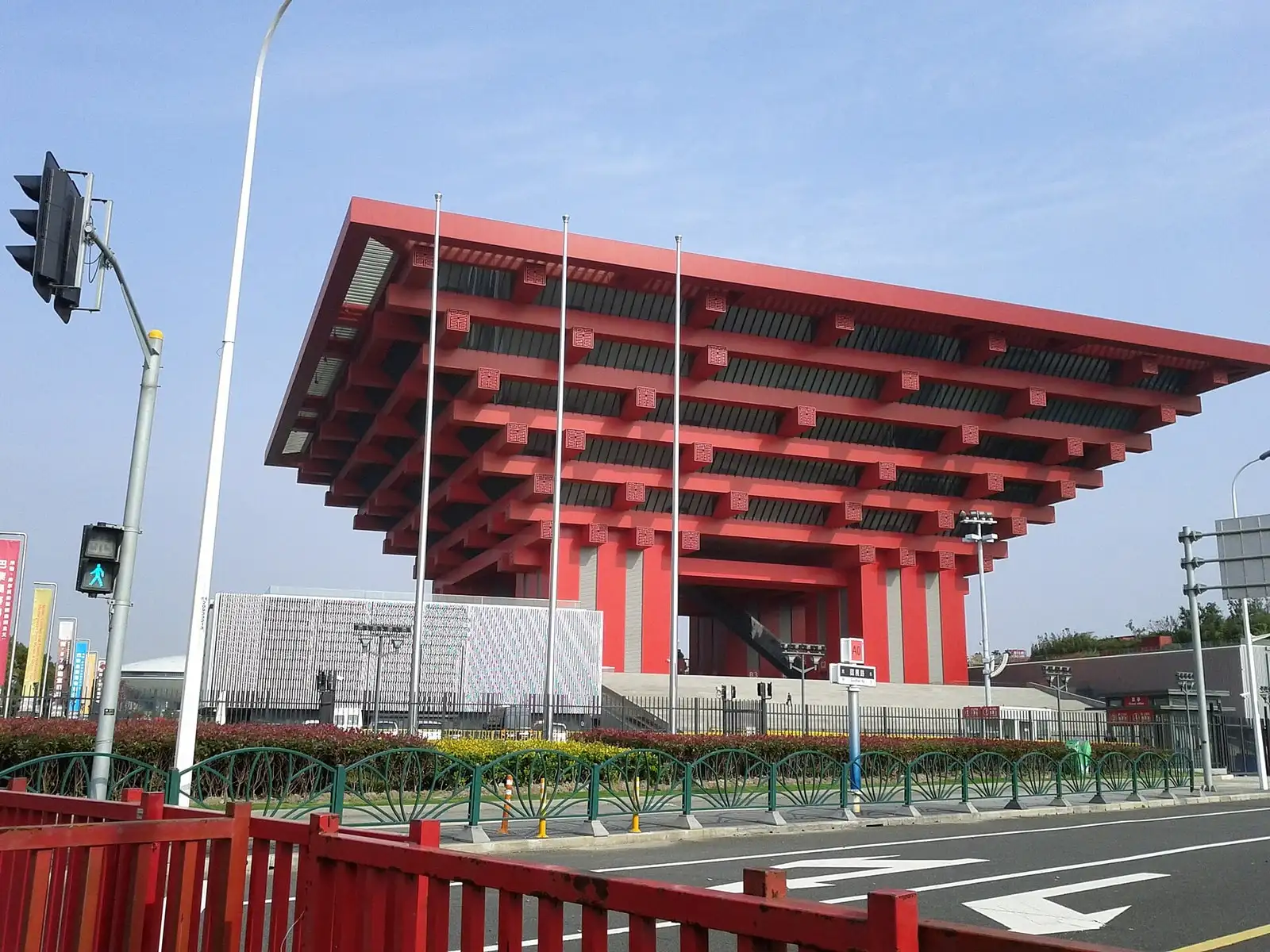The red stacked roof brackets of the China Art Museum above a road crossing.