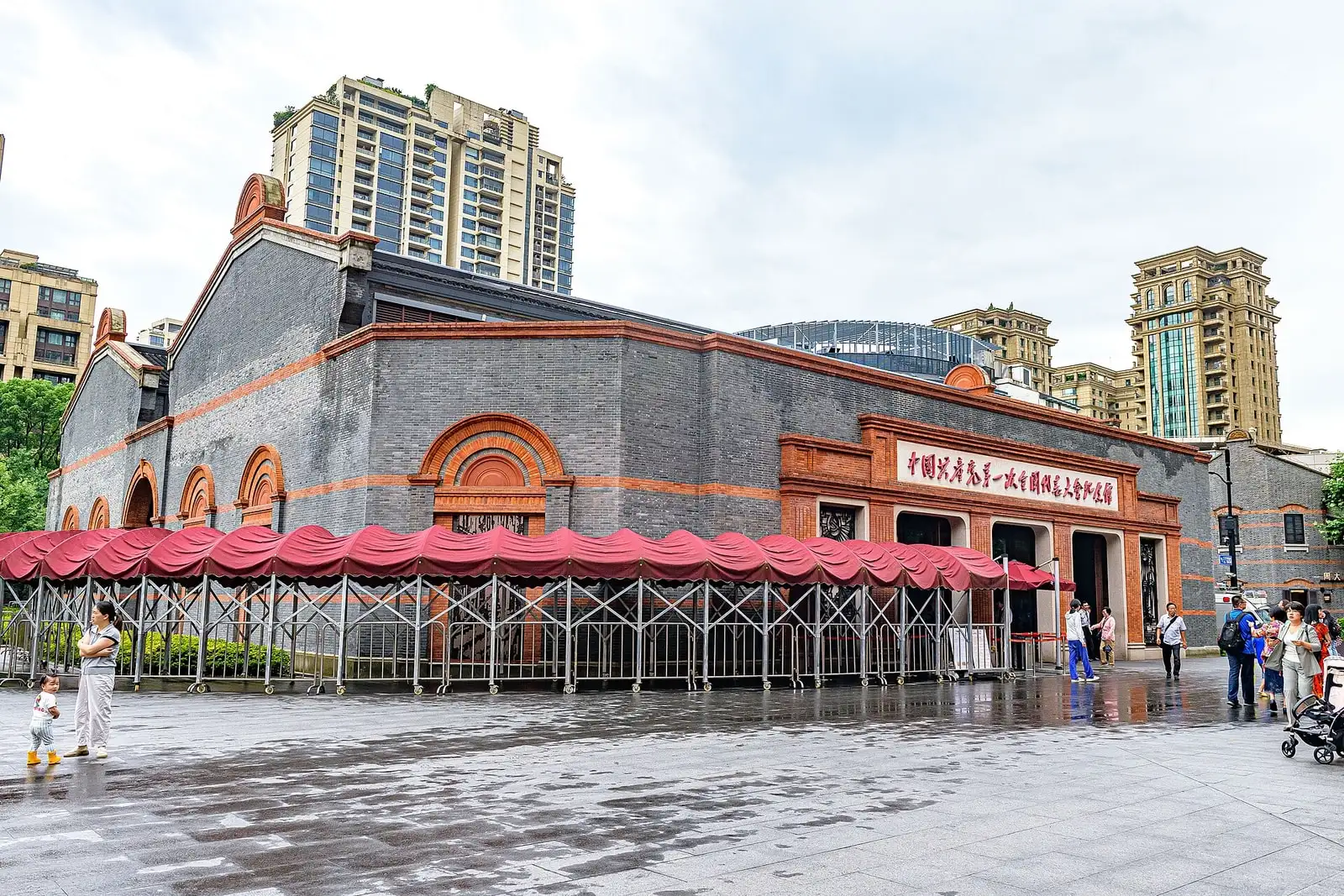 The red-brick and grey-stone exterior of the First CPC Congress memorial hall, beside a paved public space.