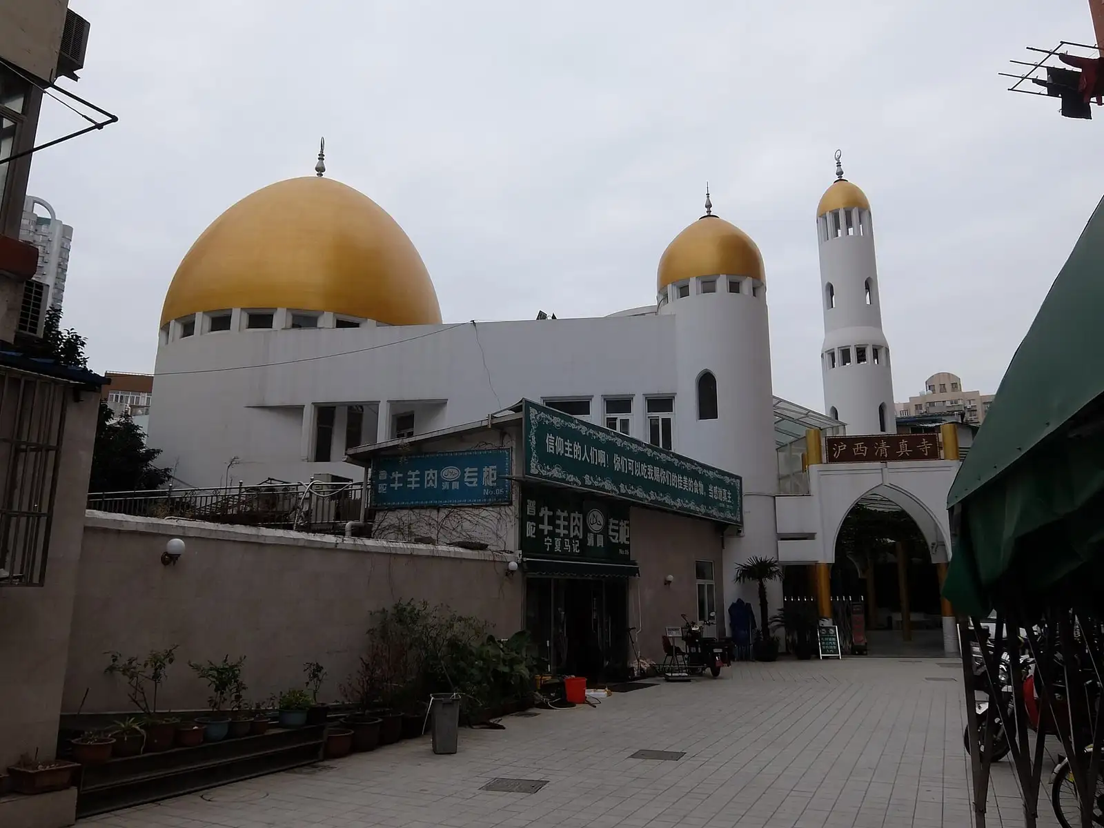 The white buildings and golden domes of Huxi Mosque seen across its courtyard.