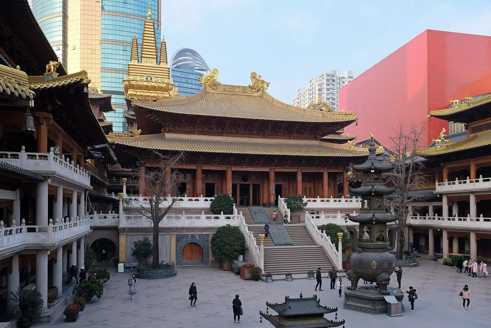 Jing'an Temple courtyard, with golden roof ornaments, broad stairs and modern towers behind.