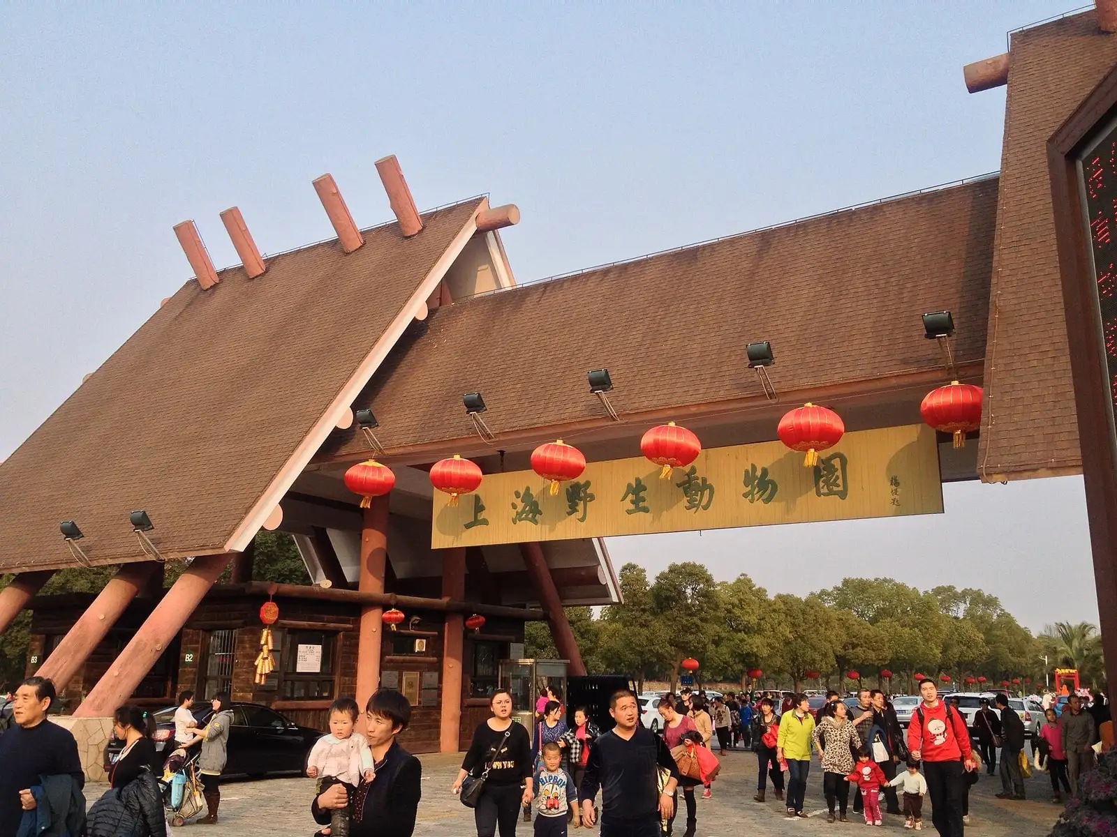 The main entrance of Shanghai Wild Animal Park, with a sloping roof and visitors below its sign.