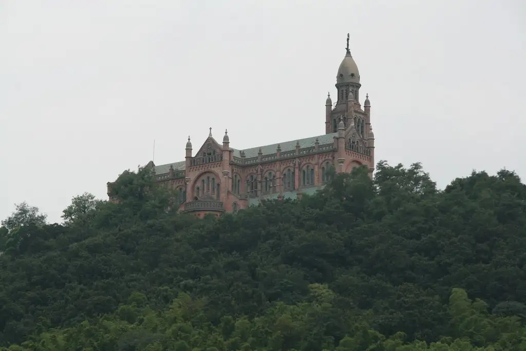 Sheshan Basilica rising above a wooded hillside, with its brick facade and bell tower.