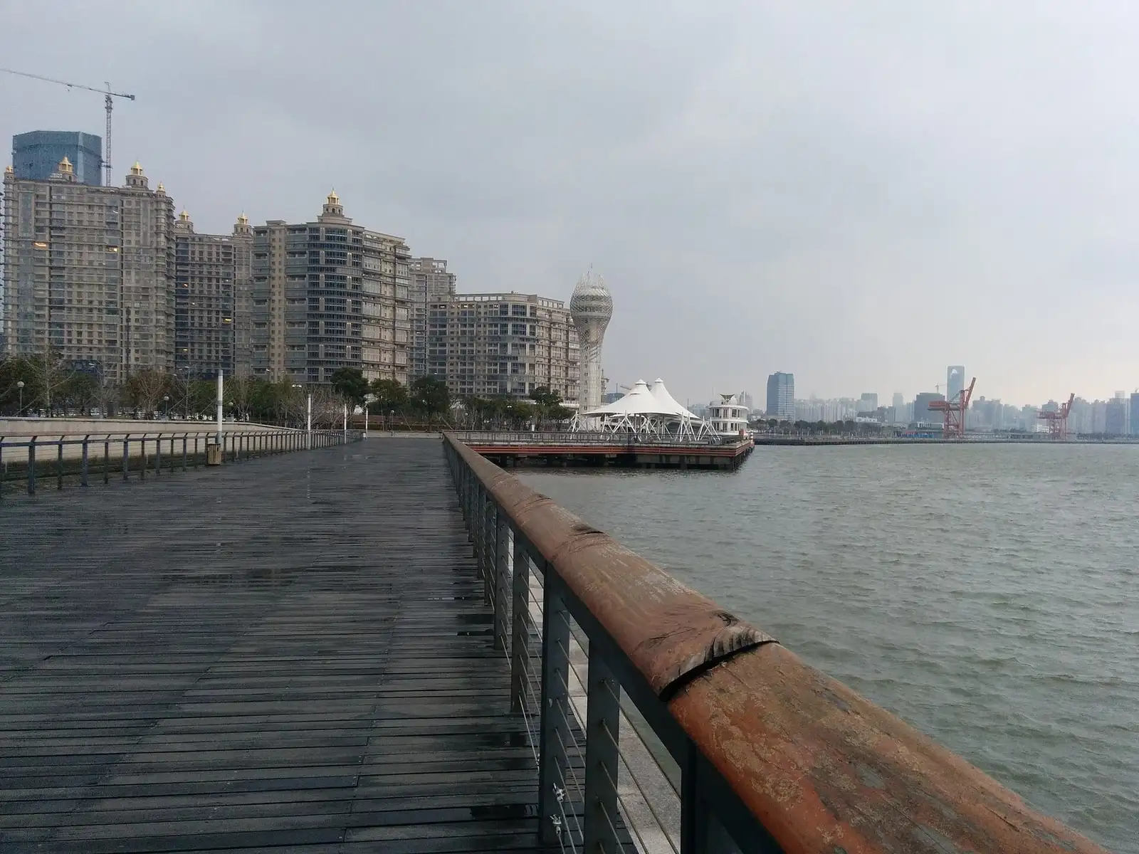 A wooden waterfront walkway and railing beside the Huangpu River on Xuhui Riverside.