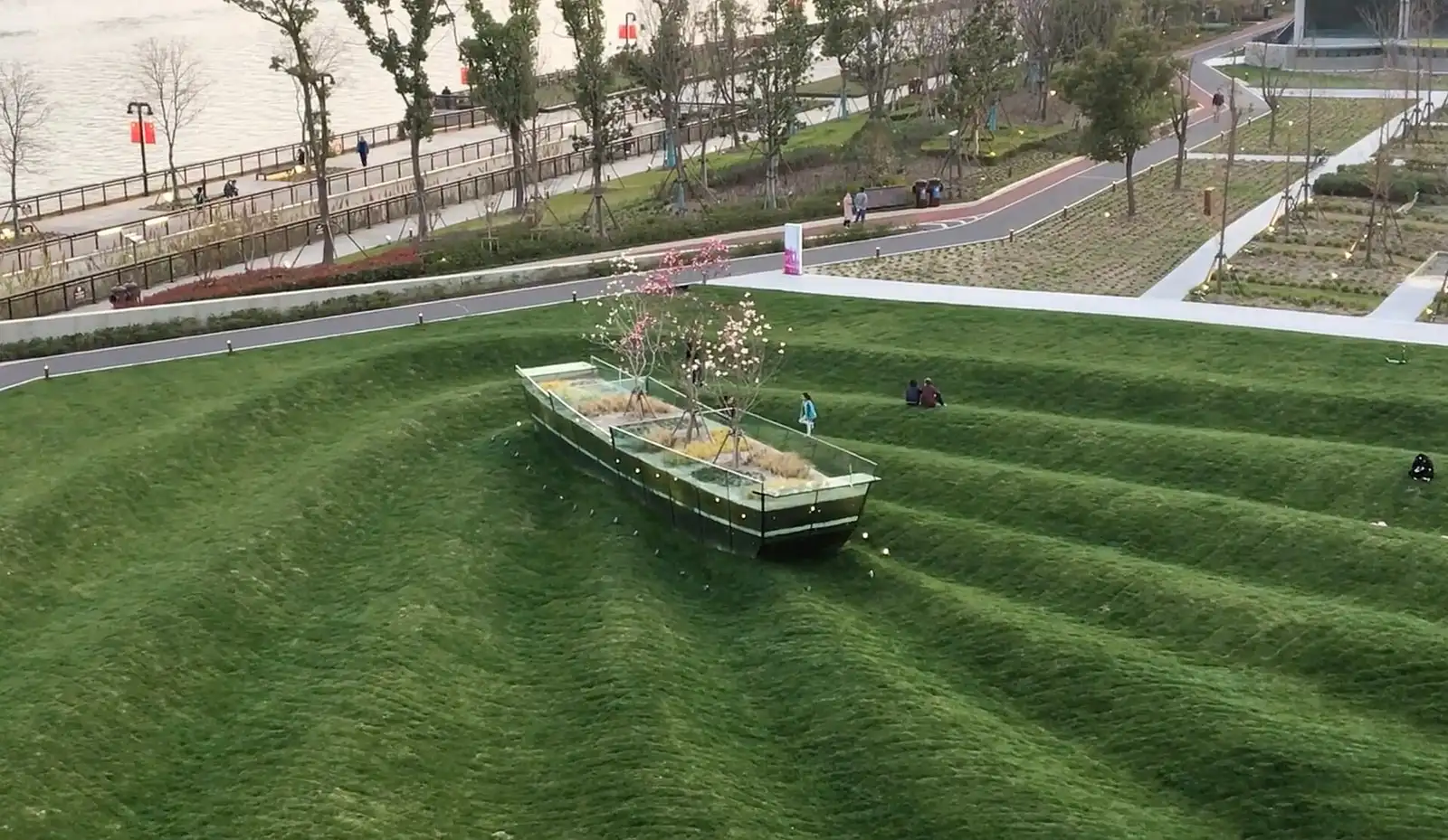 Landscaped grass terraces on Yangpu Riverside, with paths and the river beyond.