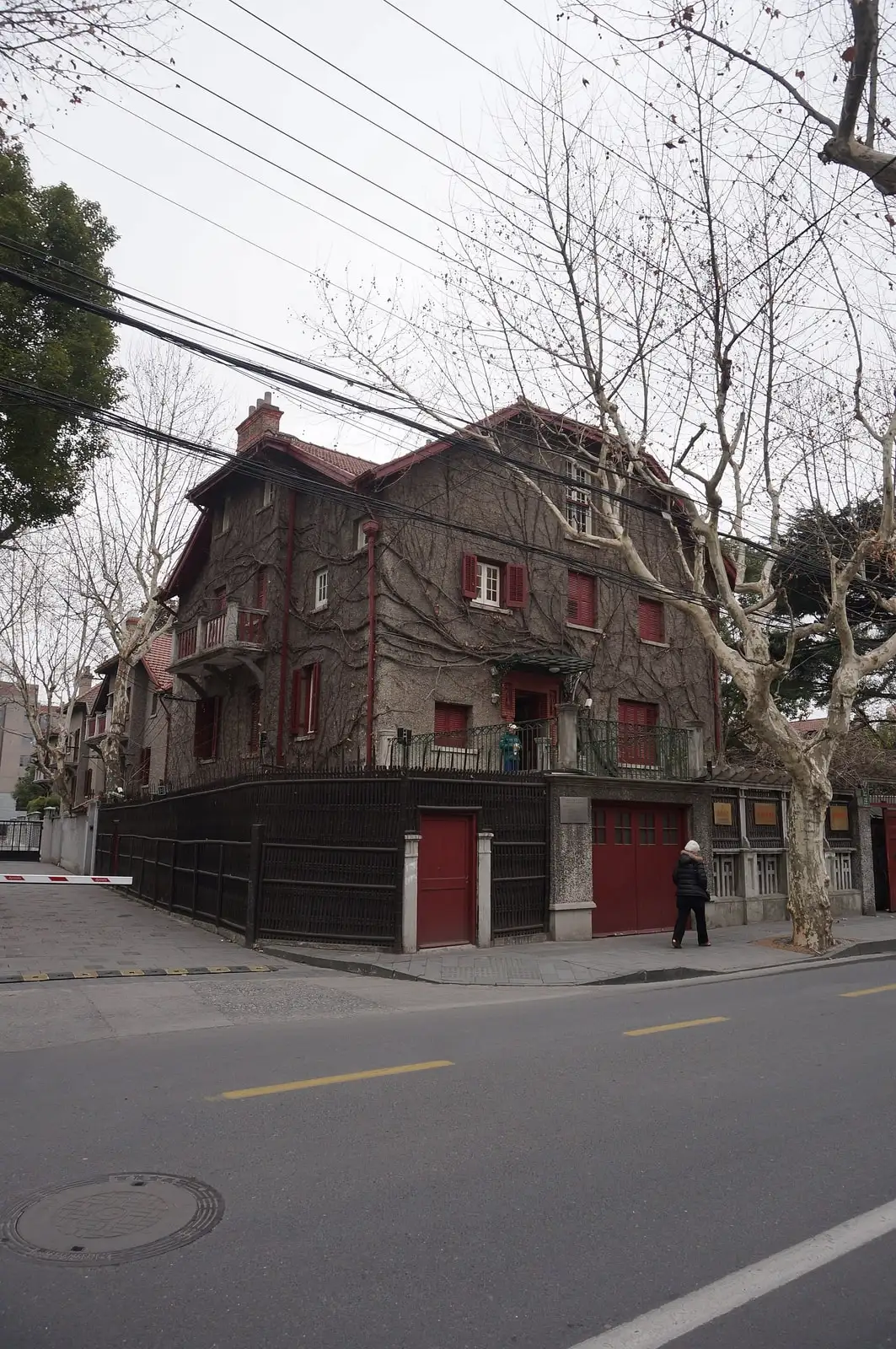 The brick exterior of Zhou Enlai's former residence on a street corner behind a red boundary wall.