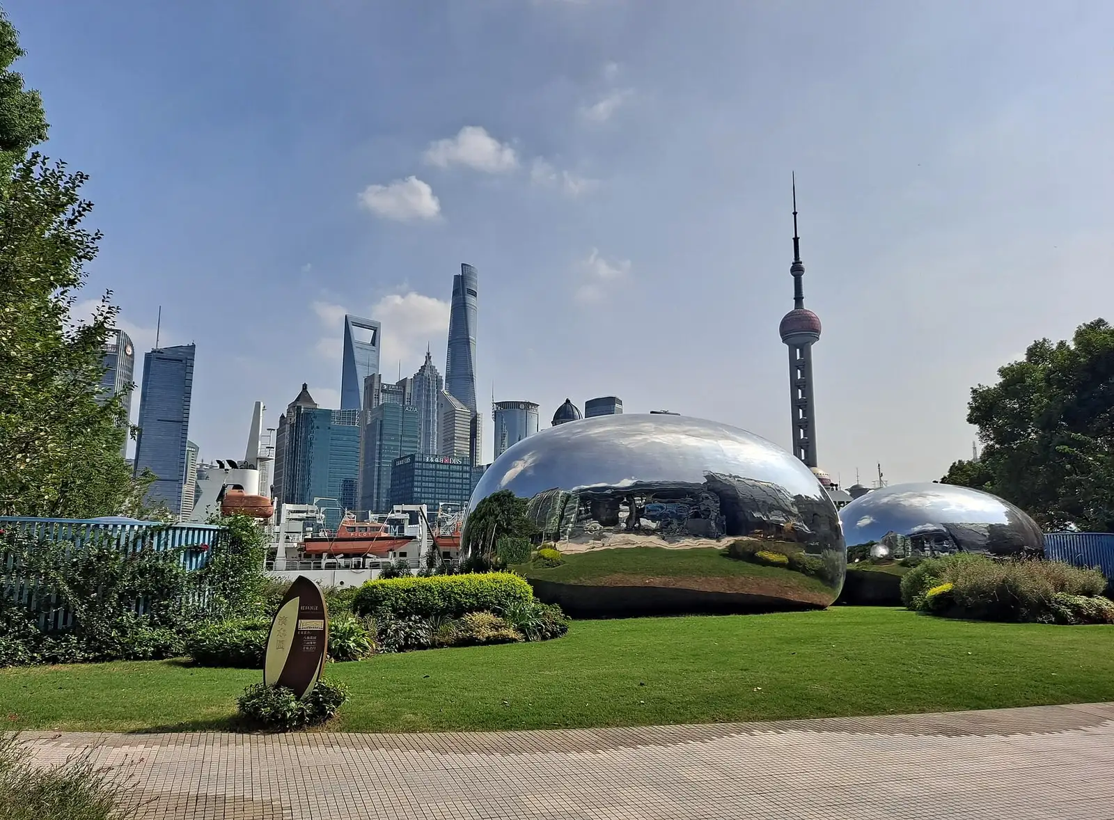 A garden on the North Bund, with curved silver structures and the Pudong skyline across the river.